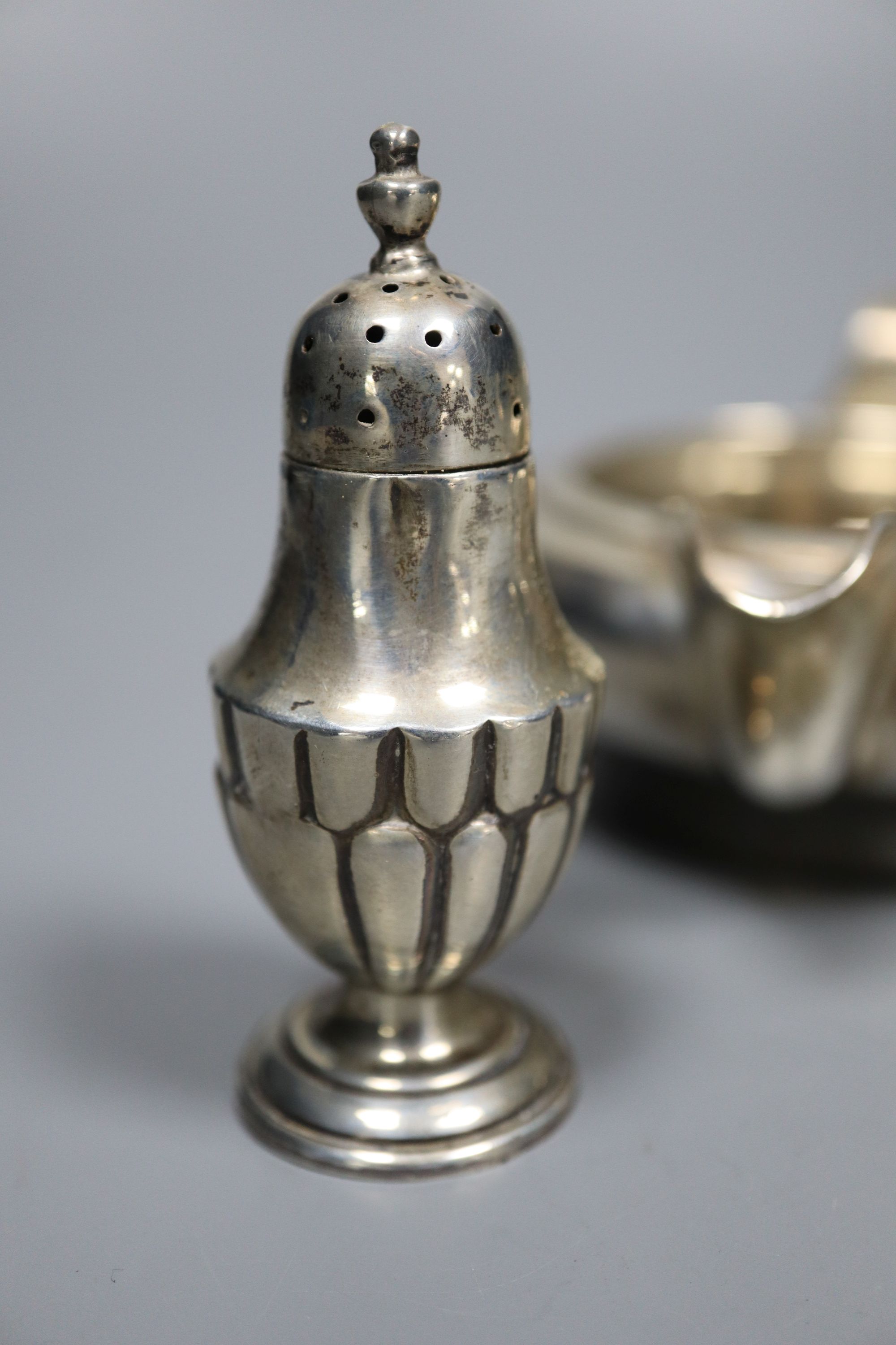 A George V silver sugar bowl and cream jug, London 1935 and a pair of Edwardian silver salt and pepper pots, London 1905,